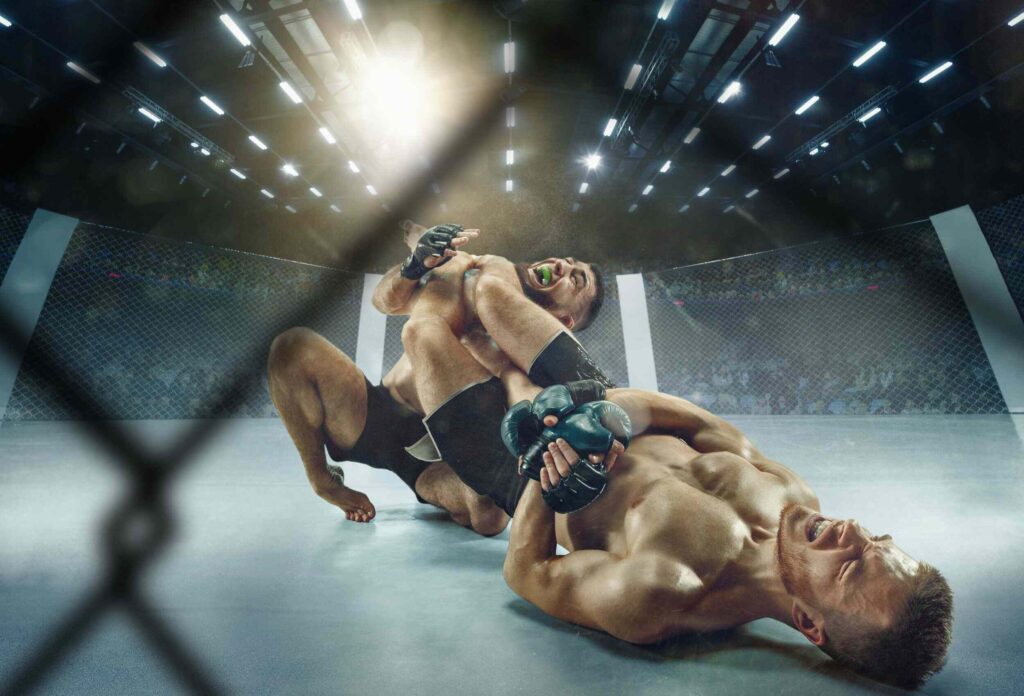 photo of 2 MMA fighters in a cage, a fighter in blue gloves takes a "triangle" painful hold of a fighter in black gloves