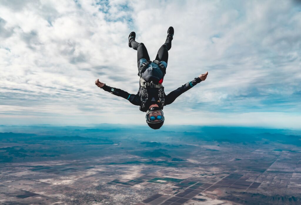 a man in a skydiving suit flies head down in free fall at high altitude