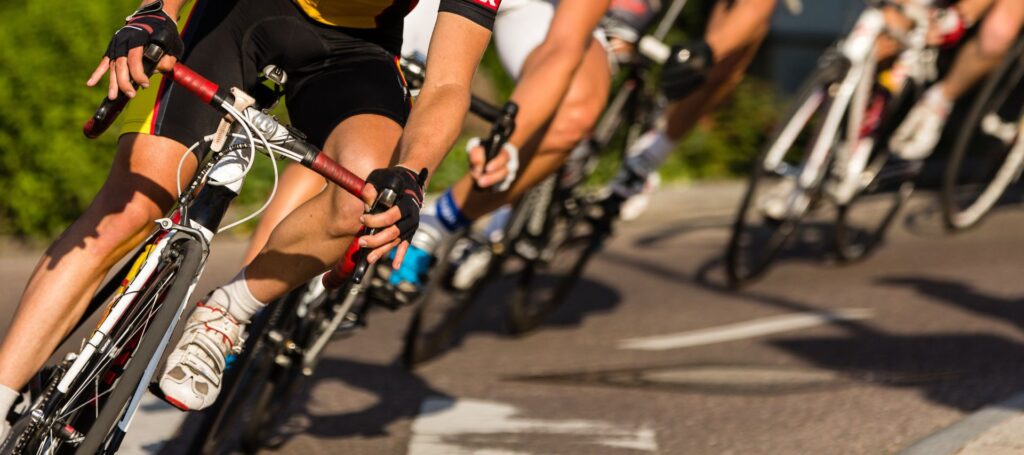 A photograph of cyclists on road bikes, taken below the chest of the athletes performing a smooth left turn