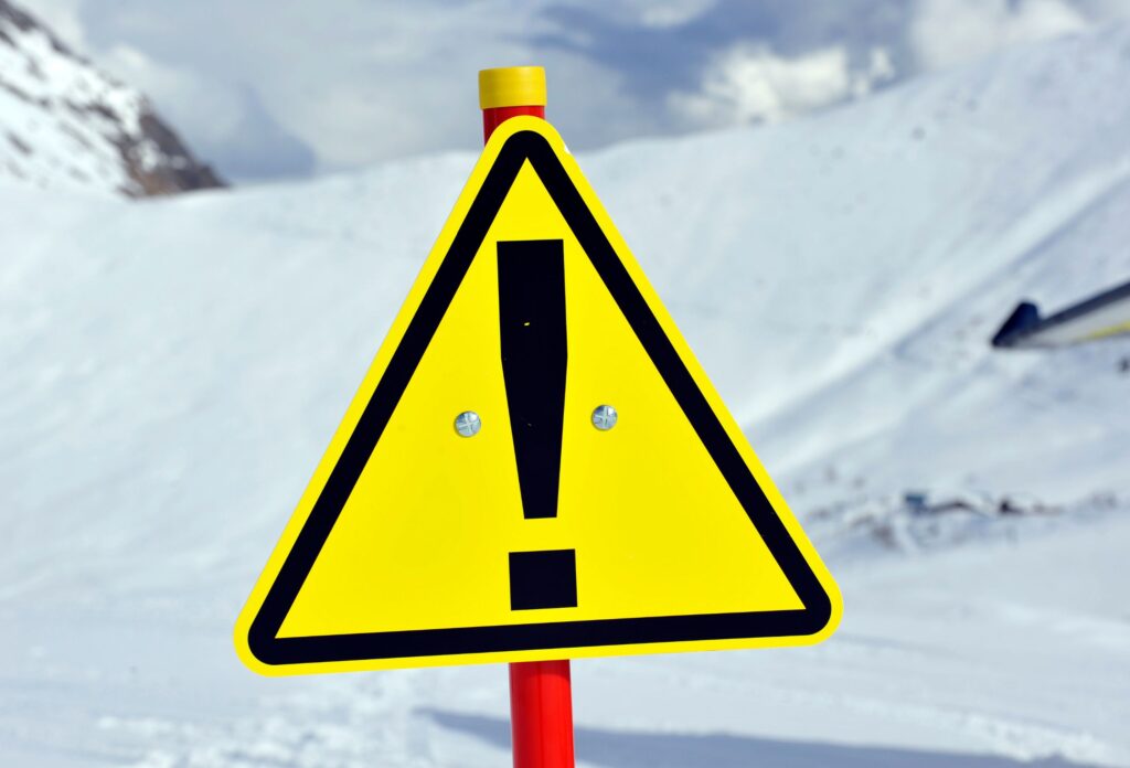 exclamation point on a yellow background sign set in snow at a ski resort