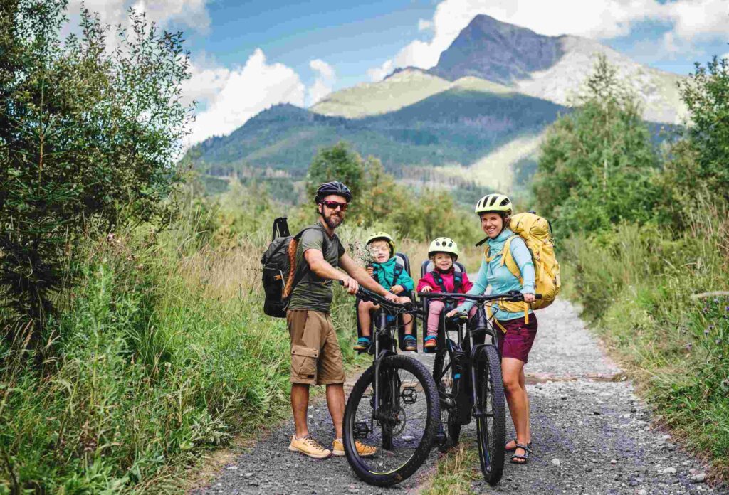 a family with 2 children went on a bike ride on 2 bikes, children sitting in special child seats for bikes, photo against the background of a beautiful view of nature