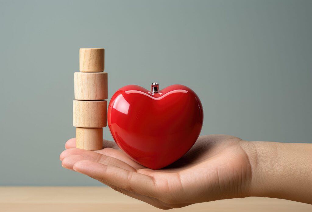 A close-up of a hand with a beautiful toy heart on it and a wooden coin-shaped structure showing the importance of insurance