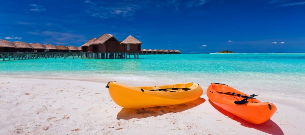 Photo kayaks on the sand, with beautiful blue water and pier houses in the background