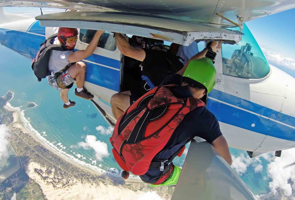 Extreme skydivers hold on to the outside of an airplane while preparing to skydive