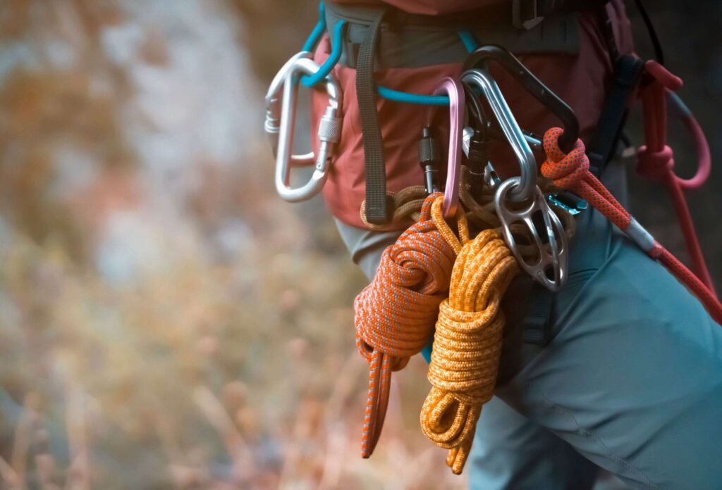 a climbing belt with carabiners and ropes on a man in blue pants.