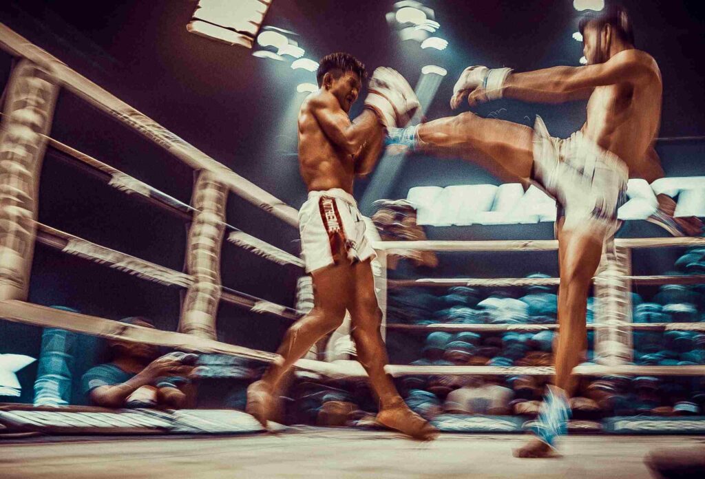 man delivers a powerful kick during a muaythai fight