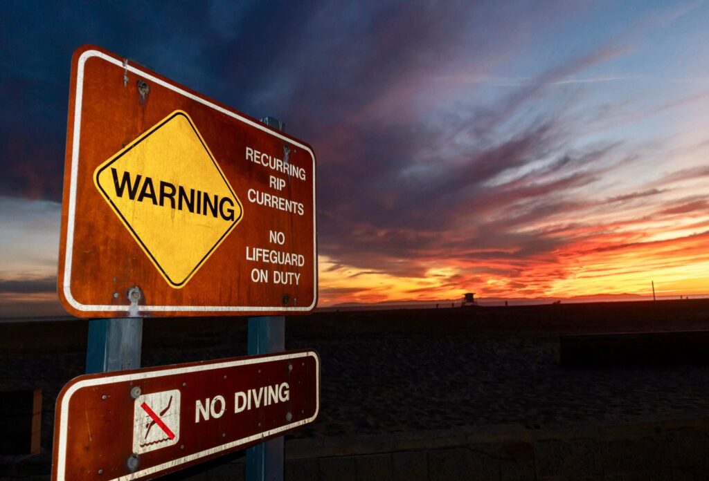 photo of a sign in the evening prohibiting diving due to risk of injury and death