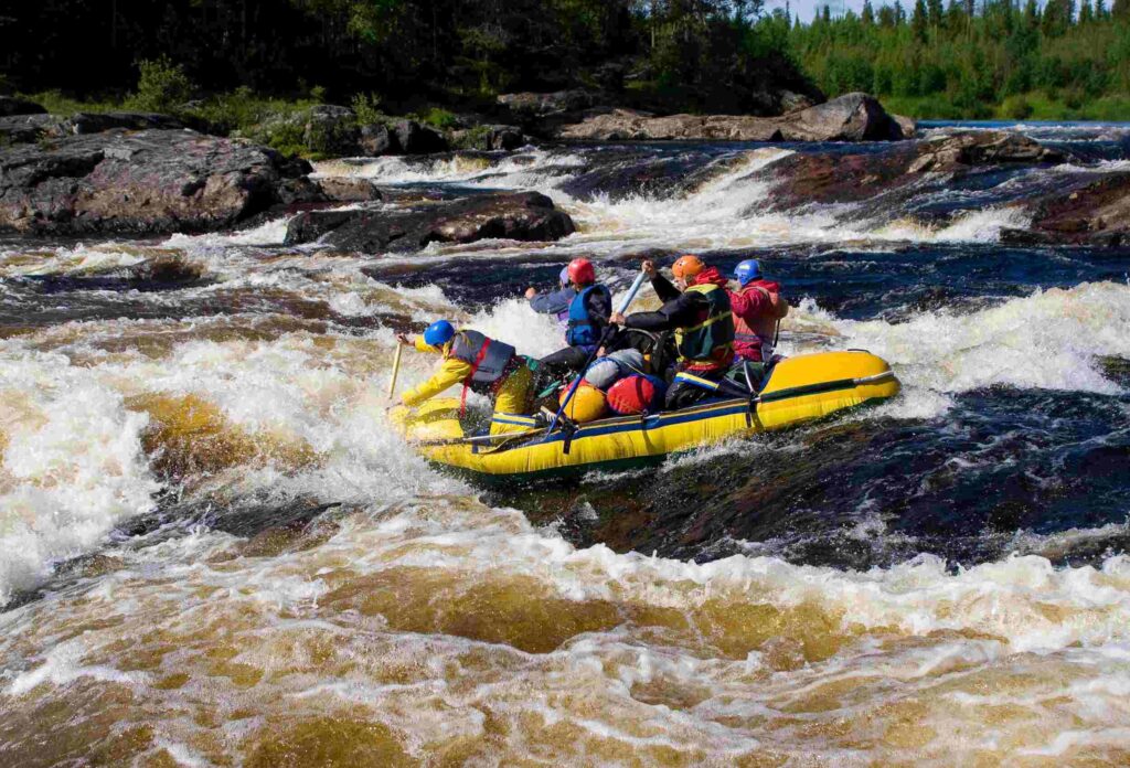 a yellow raft with 4 people on it goes through difficult class 3 rapids on whitewater with rocks