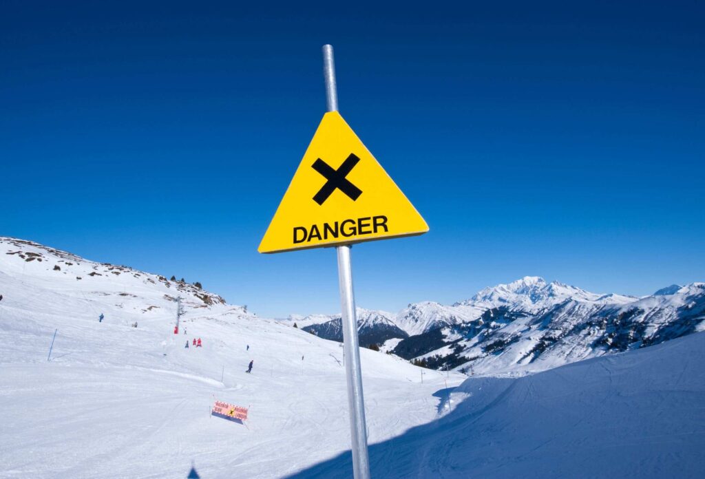 at the bottom of the ski slope there is a sign warning of danger with the inscription "danger"