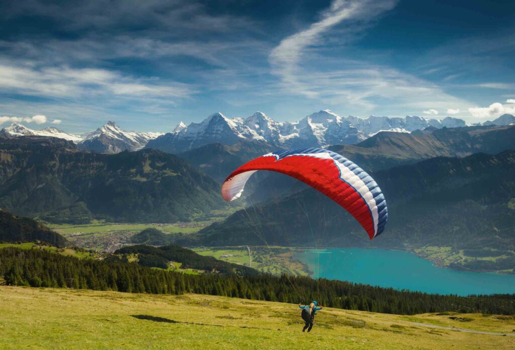 a paraglider plans to fly a tricolor paraglider against a backdrop of incredibly beautiful views of snowy mountains, forests and lakes