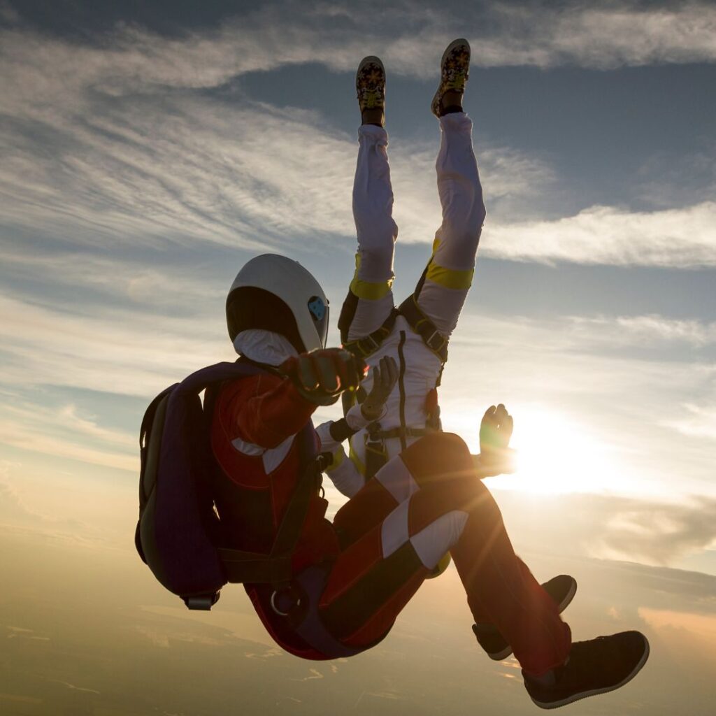 two skydivers flying in free fall against the background of the sunset