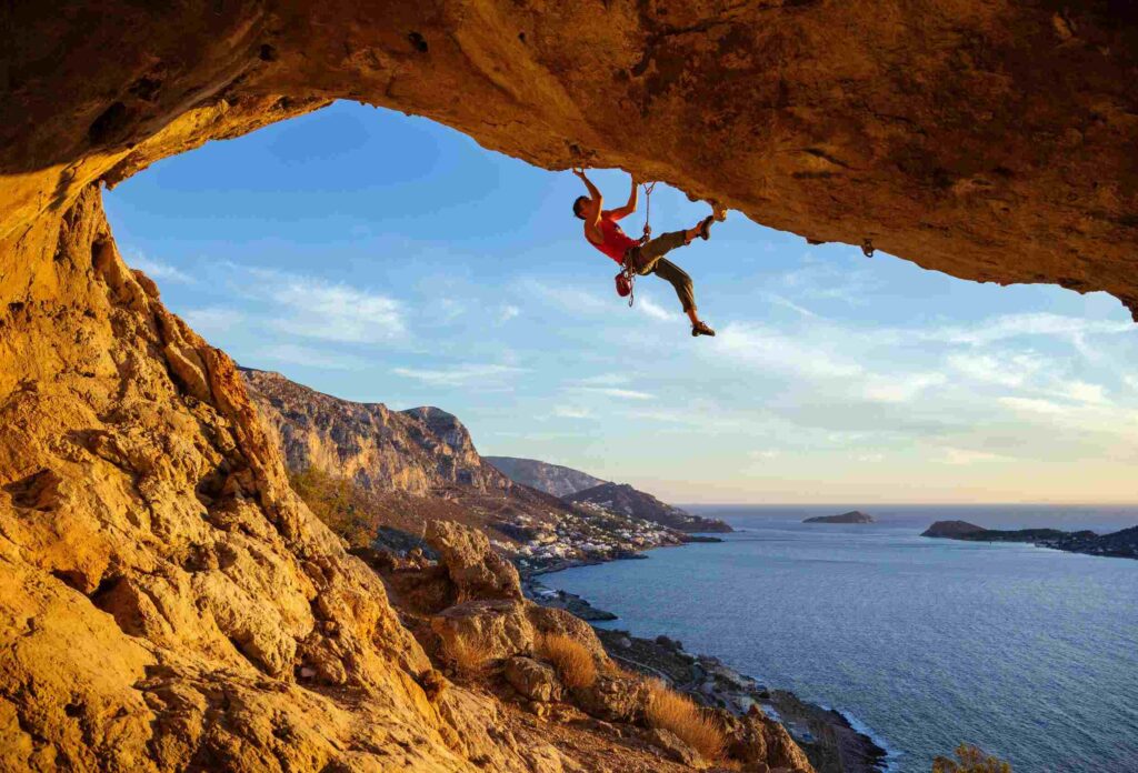 A man is climbing a very difficult route with a difficulty level of 5.14 on the Frank scale against the backdrop of a marvelous view