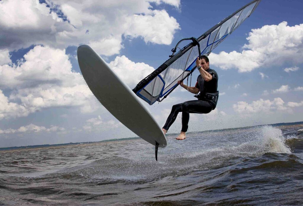 man performs dangerous jumping stunt while windsurfing on water